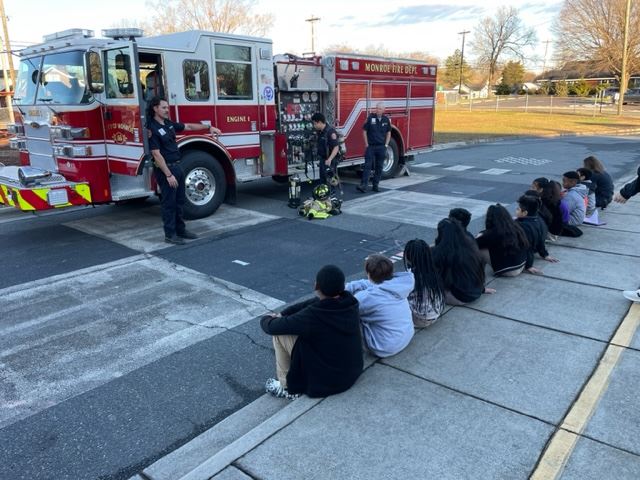 A firefighter showing the fire truck to a group of students