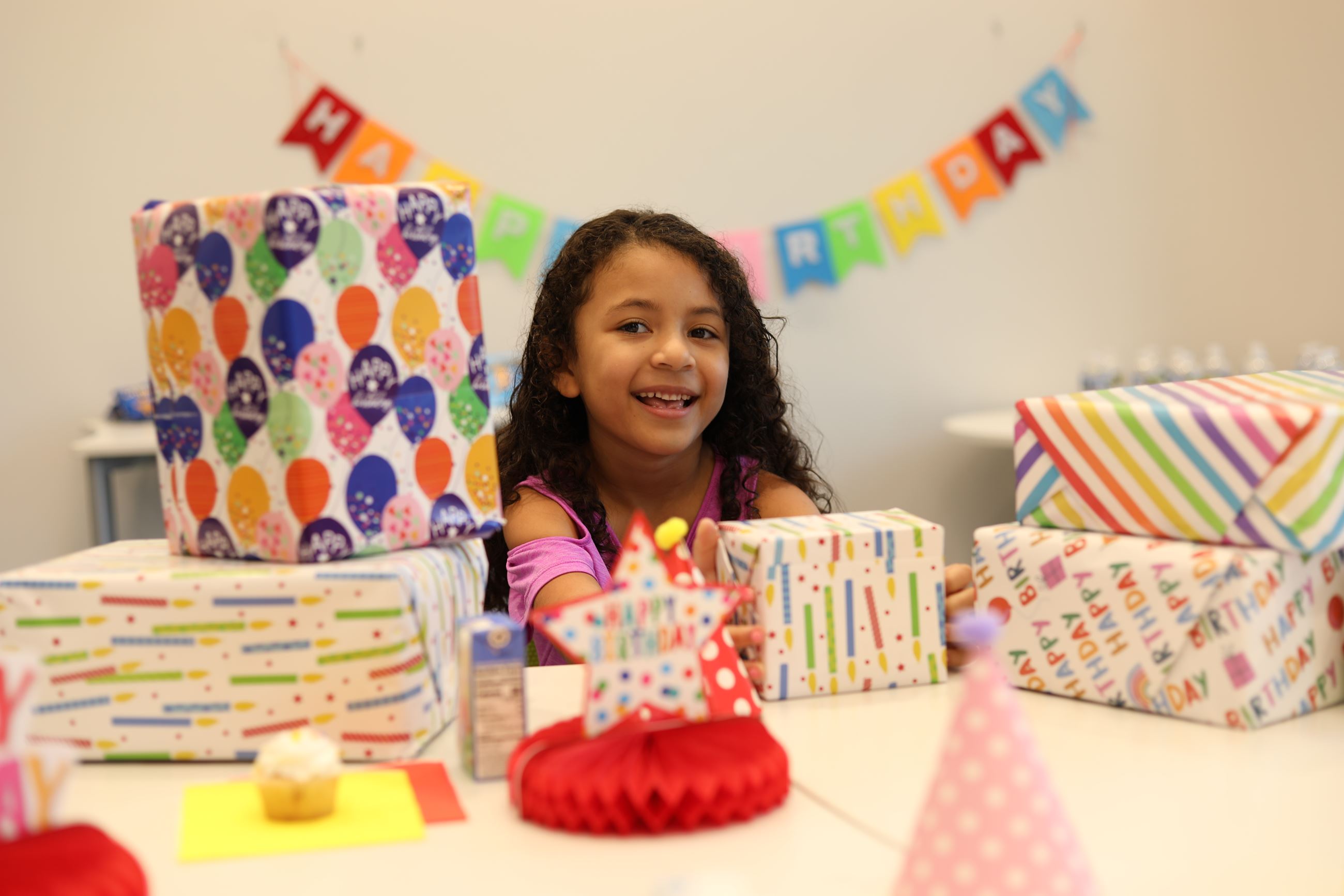 Birthday Girl smiling and presents piled on the table