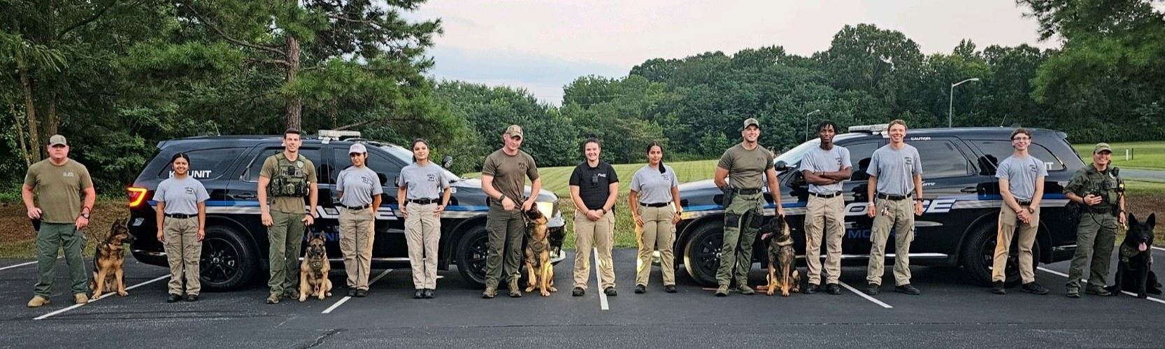 Police Explorers stand in a line outside with K-9 officers and their dogs.