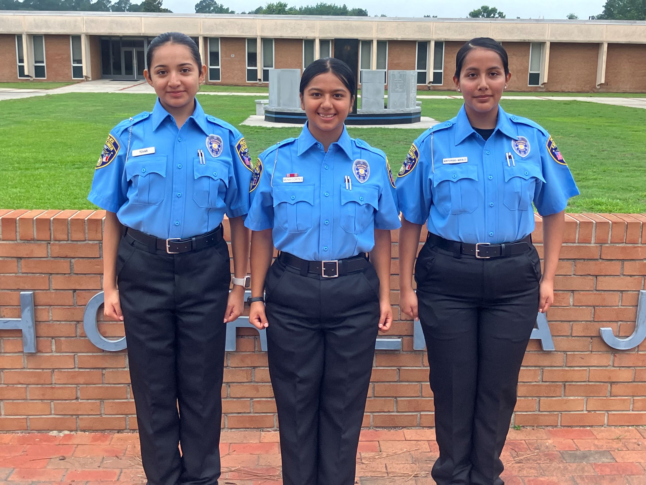 Three Monroe Police Explorers stand outside in full uniform.